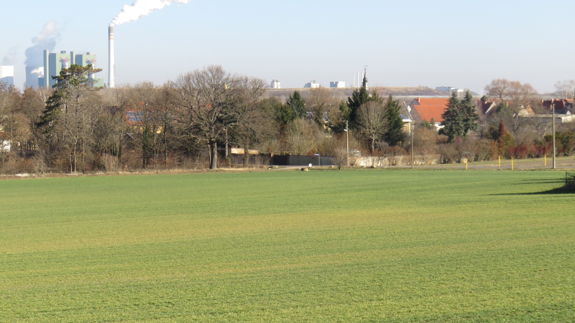Das Foto stellt einen Blick in Richtung Nord auf den im Tal gelegenen Ort Knapendorf mit einem Teil der Silhouette des ehemaligen BUNA-Werkes (jetzt DOW) dar.