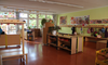 Das ist die Garderobe im Eingangsbereich. Zu sehen sind Regale für die Schuhe und die Ablagefächer mit den Haken für die Sachen der Kinder. Jedes Kind hat seinen eigenen Haken. An den Wänden hängen gestaltete Bilder von den Kindern.